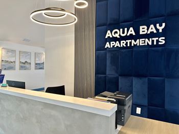 a reception area with a desk and a sign that reads aqua bay apartments